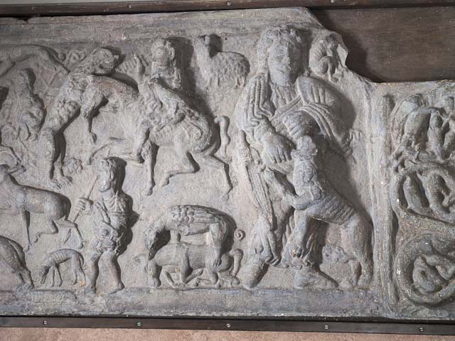A colour photo of a replica relief plaster cast showing carved people and writhing animals