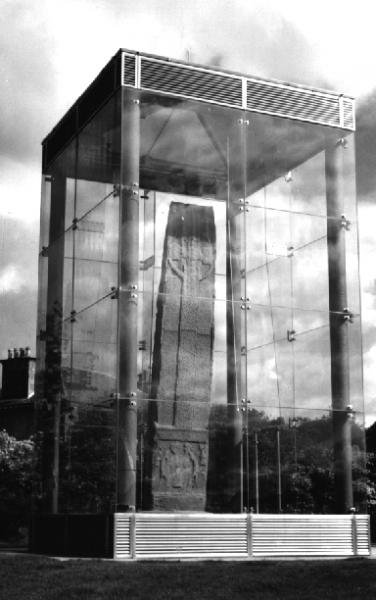 A tall standing stone stood and protected within a steel frame and glass cube