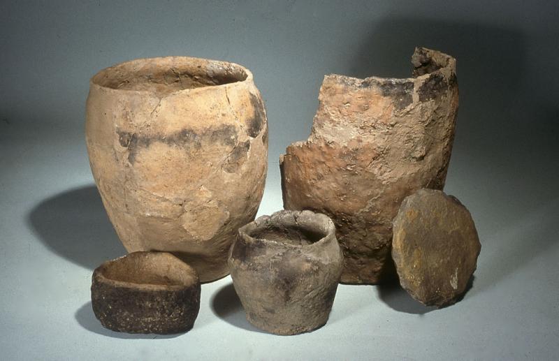 A photograph of 4 pottery vessels of different shapes and sizes and a circular flat lid