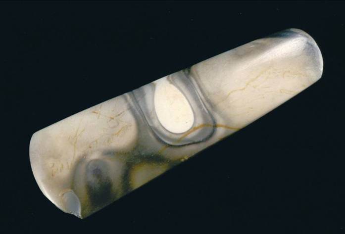 A photograph of an elongated polished axe head with a grey and brown marbled pattern
