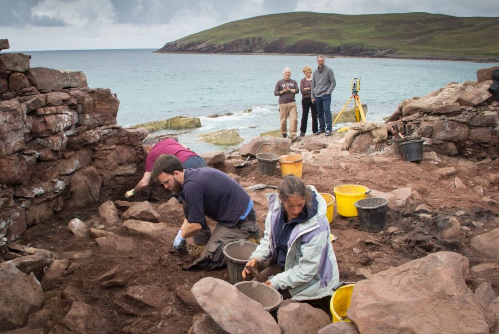 Three archaeologists excavating the interior of the broch.