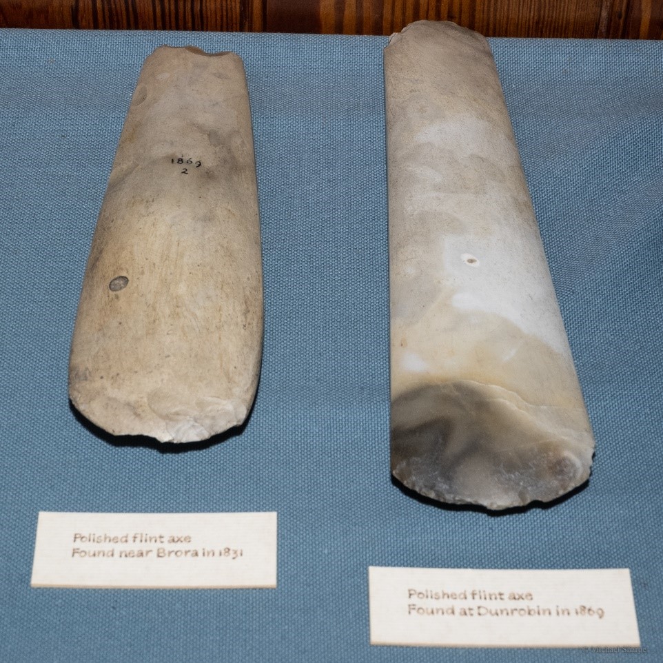 Two long stone axes next to each other on display in a museum.