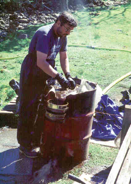 Man wet sieving soil in a barrel.
