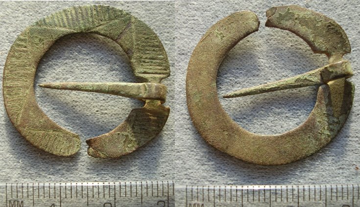 Two views of an annular brooch, the front and back. The front view shows a design of four triangles with line decoration between them.
