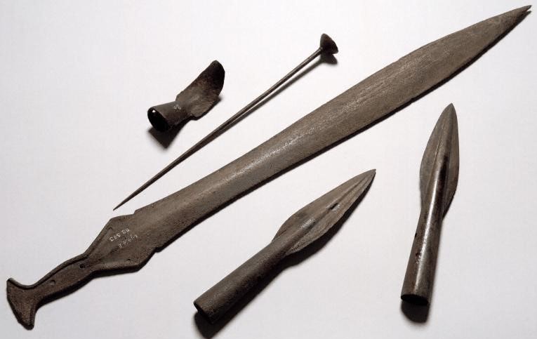 Collection of bronze objects including a woodworker’s knife, cup-ended pin, leaf-shaped sword, and two spearheads