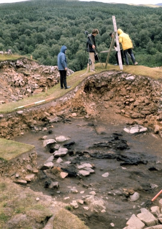 Three people standing around the debris of the excavation site