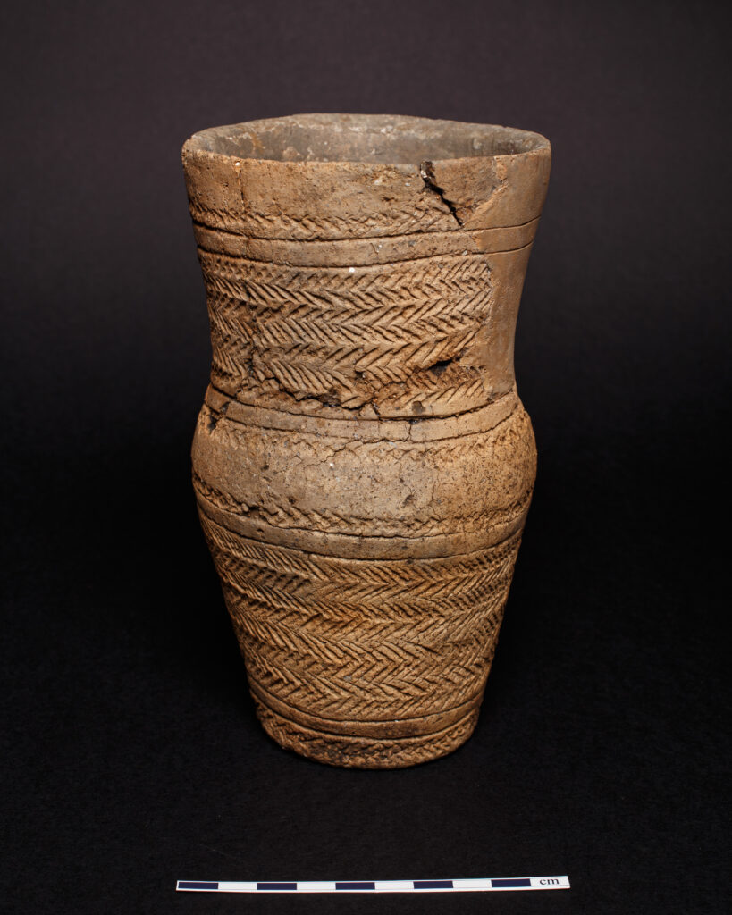 Tall ceramic vessel with incised decoration on the body and neck. 