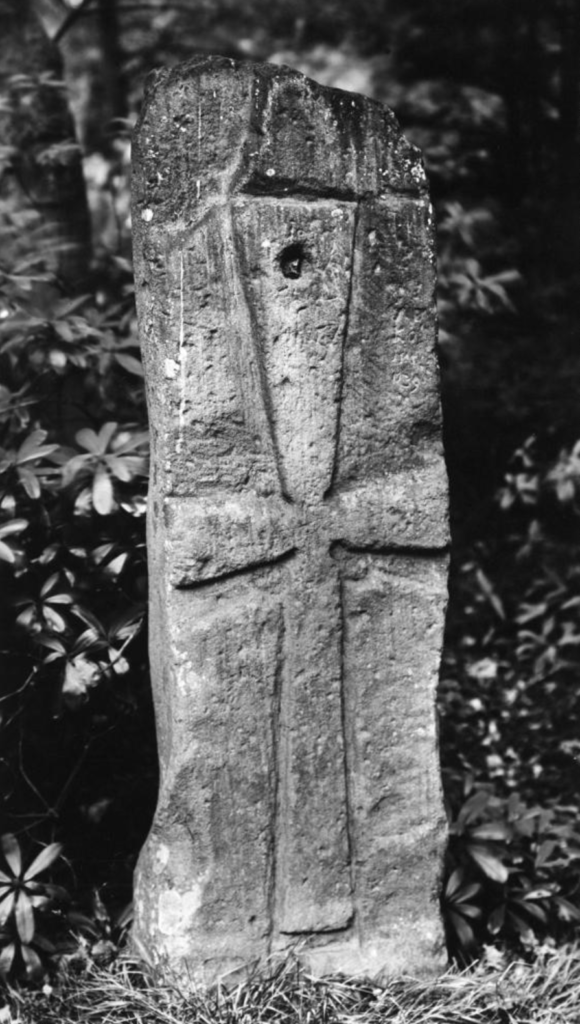 Black and white photograph of a stone with a cross-shaped carving