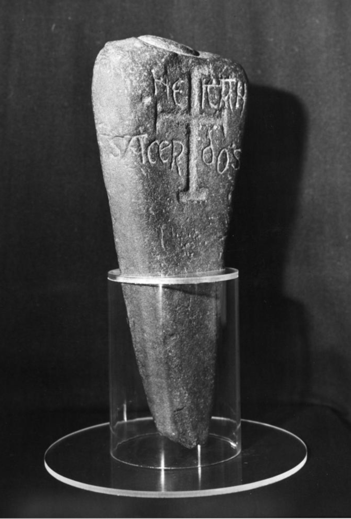 Black and white photograph of a carved stone being held up by glass