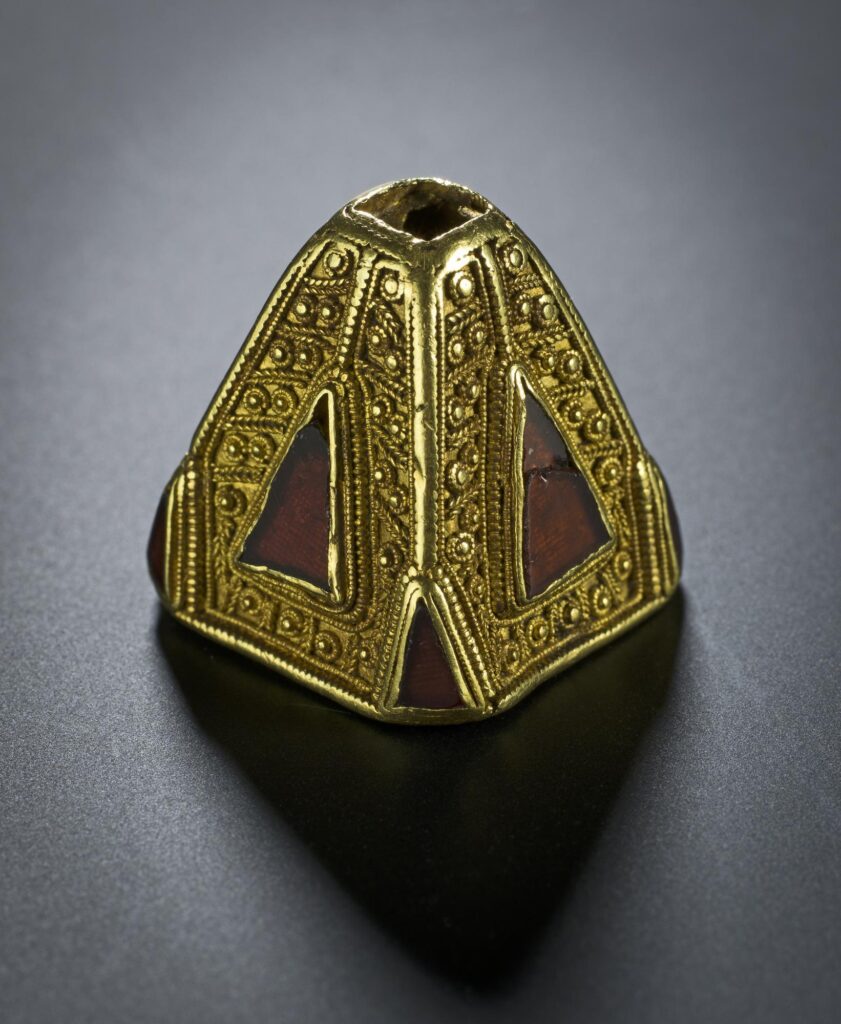 Close-up photograph of a pyramid-shaped gold and garnet ornament 