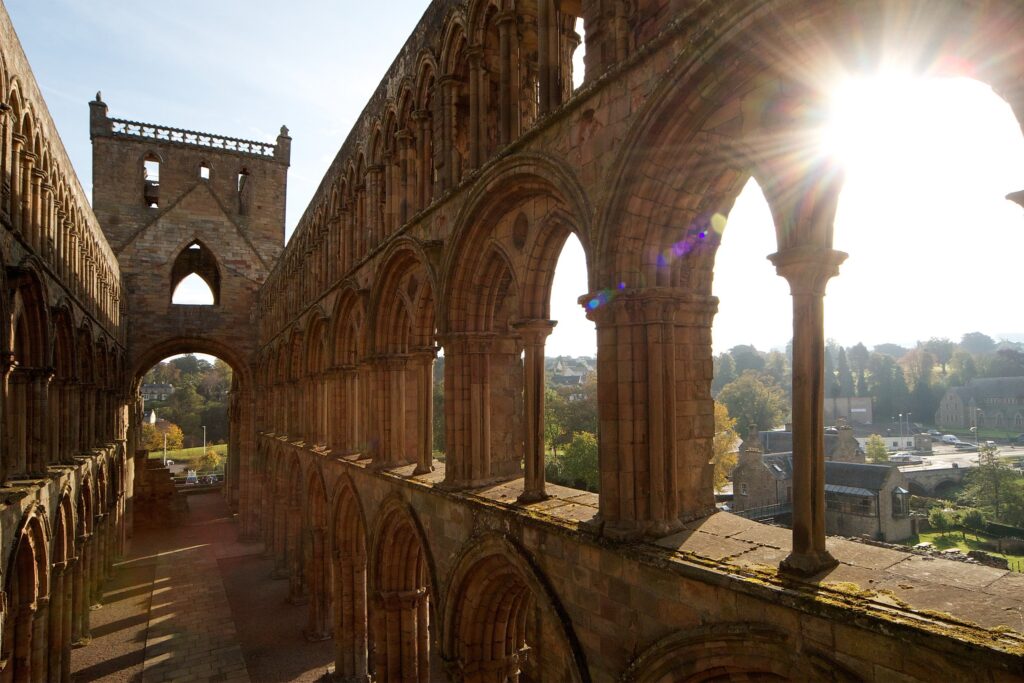 photograph from the inside of the abbey, looking out onto the town. The sun is glaring in the top right corner.