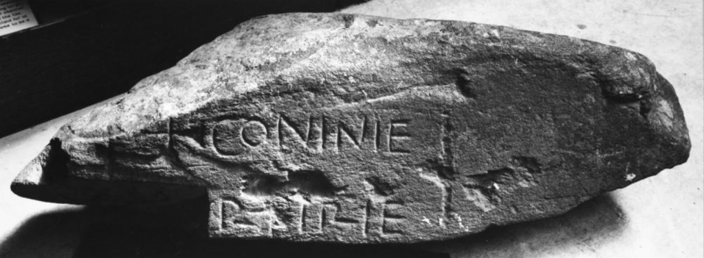 Black and white photograph of a carved stone which reads "Conine"