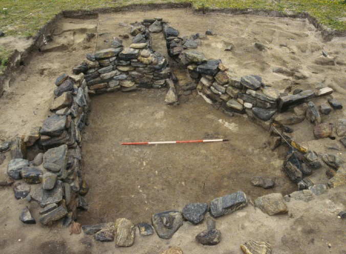 A sub-square stone structure which has been full excavated, revealing the natural soil on the floor level and one course of stone walling around the whole stucture. 