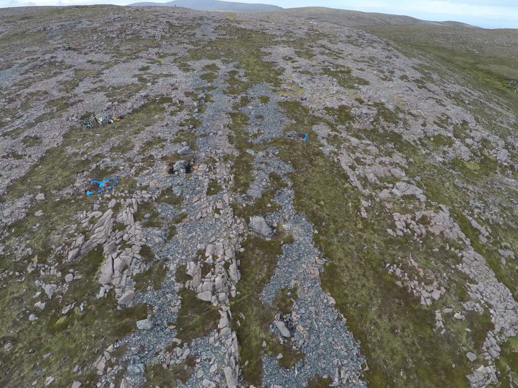 Landscape photograph showing a large area of grey stone interspersed with green moss.