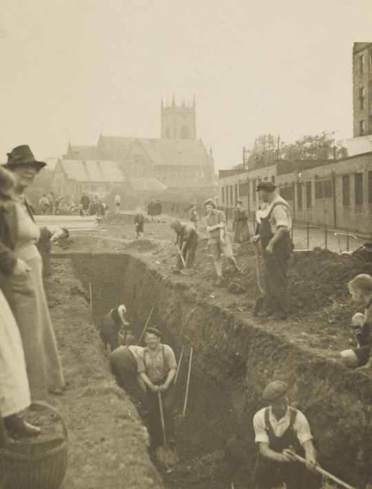 Black and white image of men digging trenches for shelters, with shovels in hand