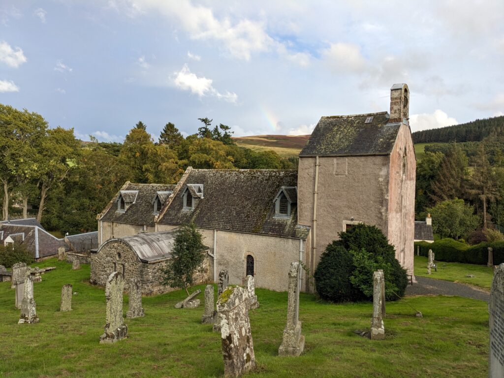 White church with three buildings within a graveyard with gravestones