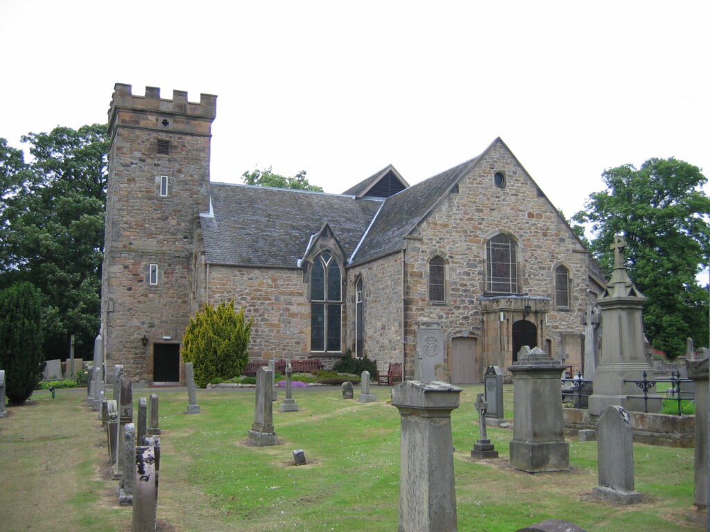 Photograph of the kirk in the background, with grave markers in front 