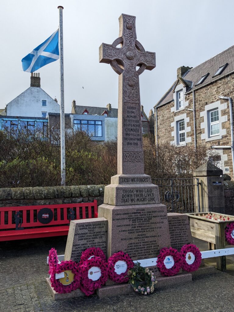 photograph of cross memorial with poppy wreaths surrounding it
