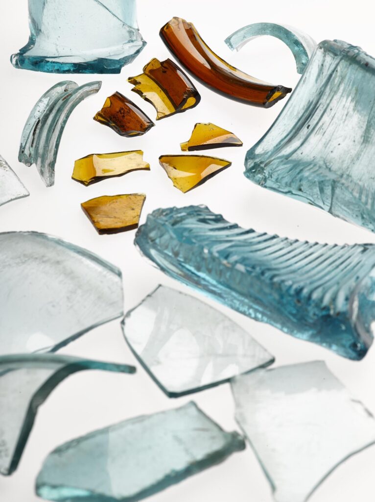 Photograph of an assortment of glass rim fragments (including blue, white and brown) photographed on a white background
