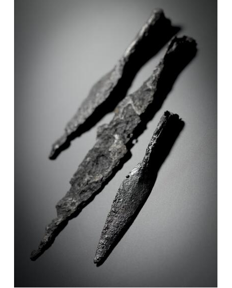 Three iron spearheads showing corrosion, photographed in black and white at an oblique angle