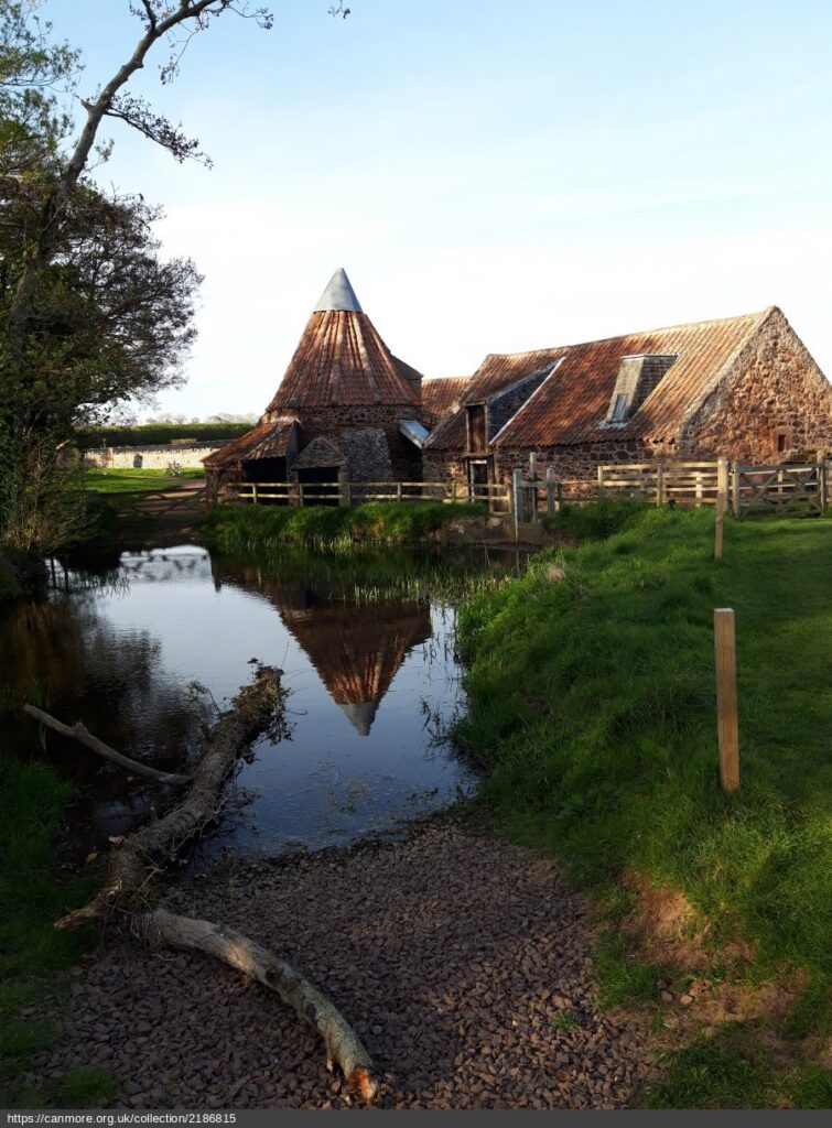 Colour photograph of mill buildings in front of river