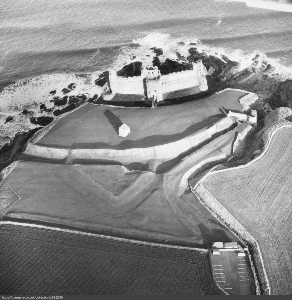Aerial black and white image of castle and defences on cliff edge