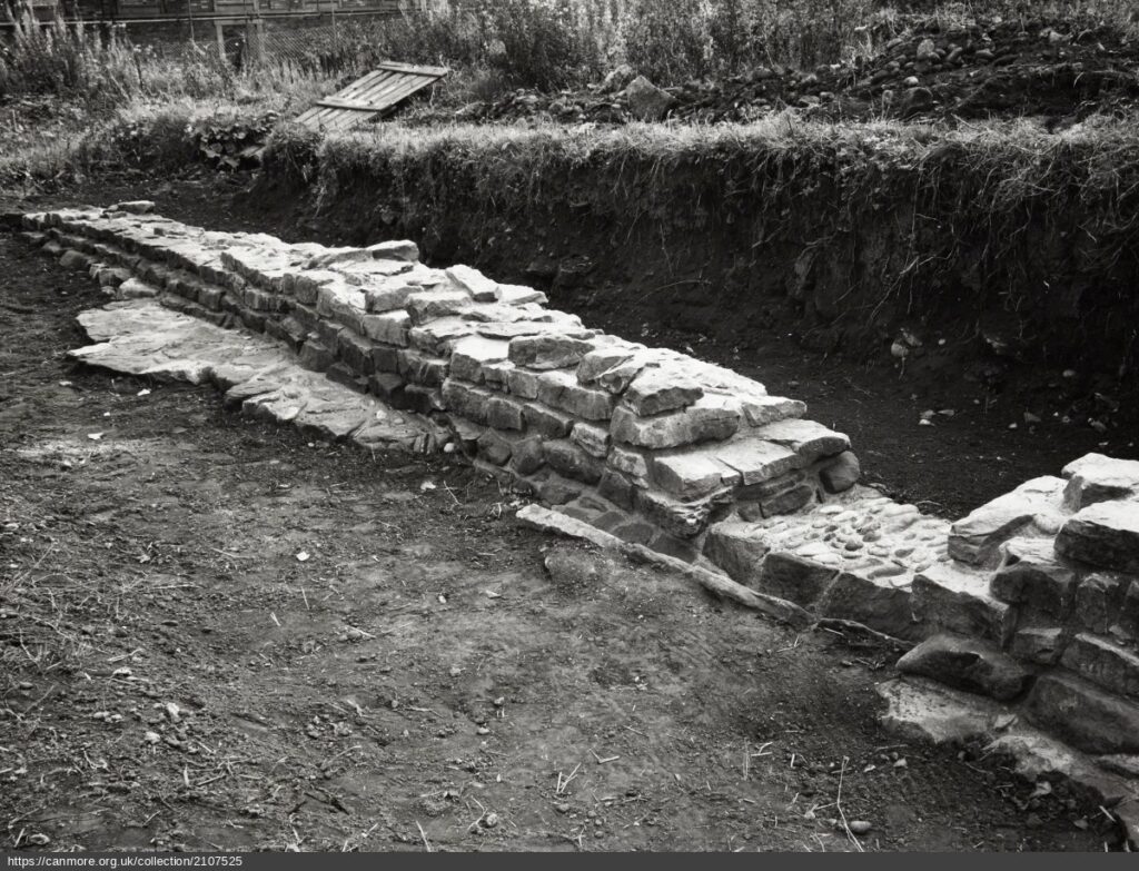 black and white photograph of stone wall during excavation