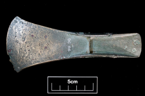 metal axehead photographed on black background