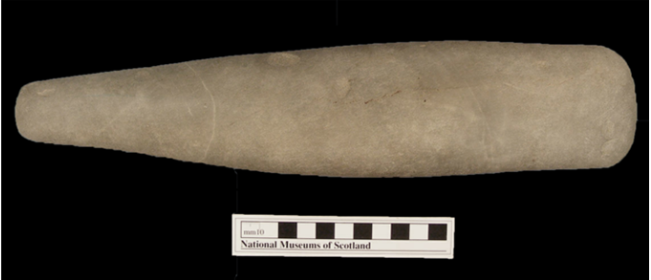 A photograph of a horizontal brown stone club about 30cm long and narrower at one end.