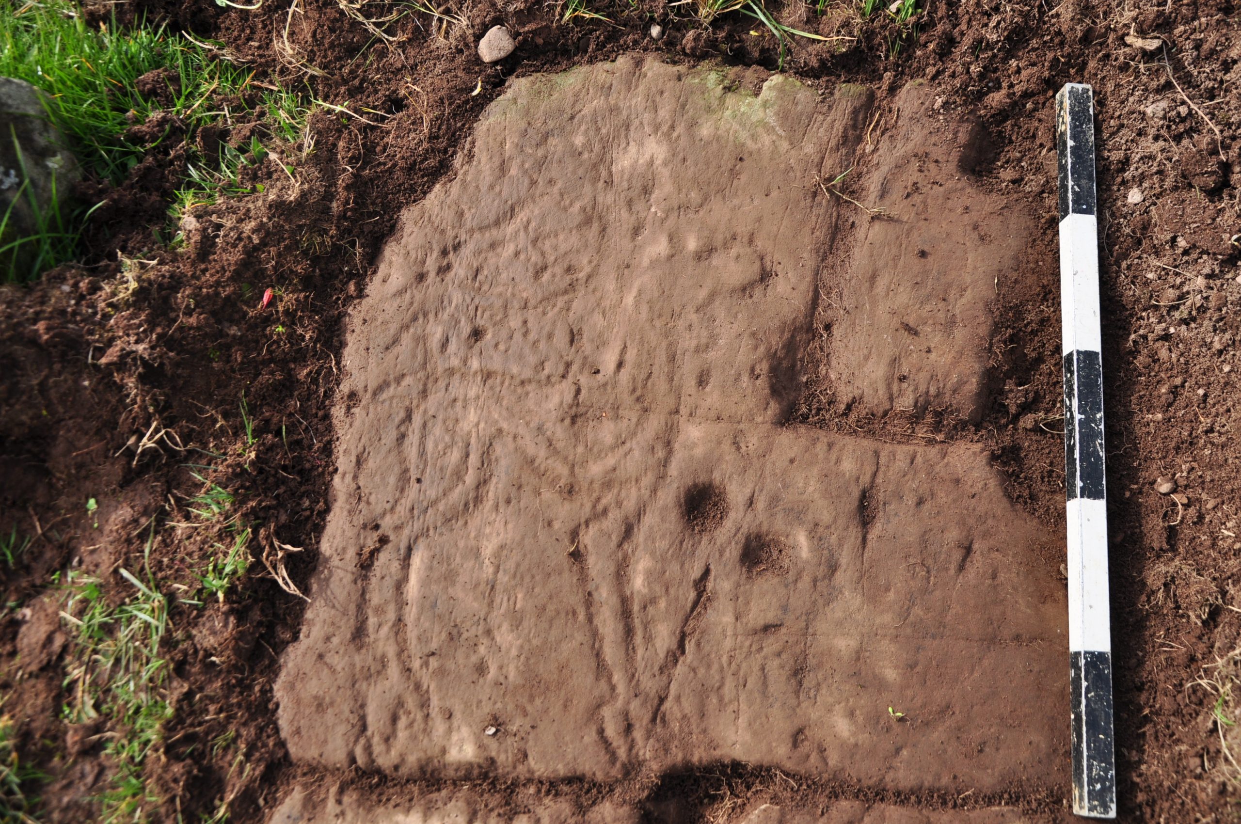 Flat redstone slab in the ground with a deer carving and cupmarks. 