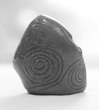 A small angular macehead with spiral details carved into it, against a white background.