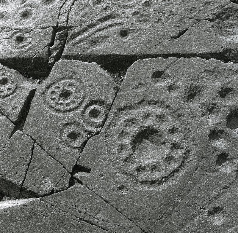 Closeup of cupmark and circle rock art on broken stone, black and white image