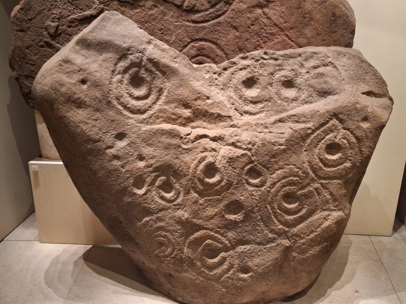 Letham Grange cup and ring stone An upright orange-brown stone with circular motifs across its surface