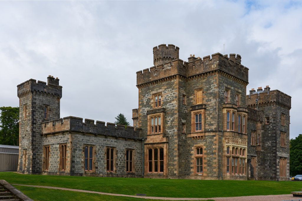 Photograph of an angular castle-like building with square towers. 