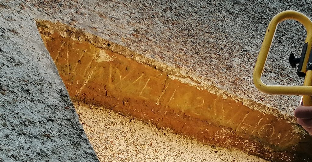 An exposed beem is bright orange-red aganst the grey floor. An inscription can be seen across the beem, though its translation is unknown.